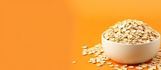 Poster - Copy space image of a bowl filled with uncooked oatmeal flakes placed on a vibrant orange background