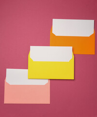 Wall Mural - Colored envelopes with white blank letters on a pink background. Creative layout