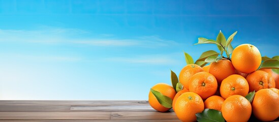 Poster - The vibrant orange fruits are displayed on a rustic wooden table creating a captivating contrast against the serene blue backdrop in the copy space image