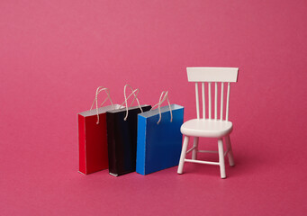 Miniature chair with shopping bags on pink background. Shopping, sale concept