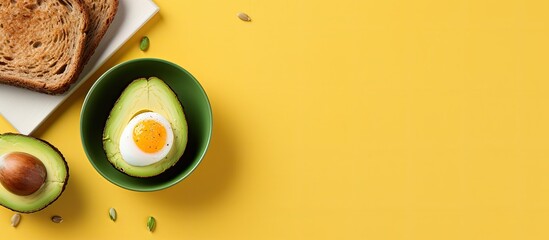 Poster - A healthy breakfast featuring avocado egg and toast is presented on a yellow background The top down view allows for a copy space image