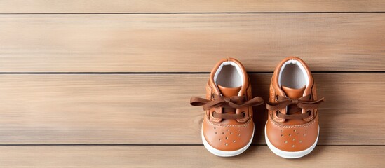 Poster - Top view of adorable baby shoes placed on a wooden background creating a charming composition with copy space for an image