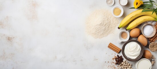 Aufkleber - A top view of a white table displays a frame filled with cake ingredients including flour banana eggs and butter leaving room for copy space