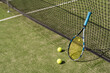 Tennis racquet and tennis balls at the net on the lines on a tennis court. 