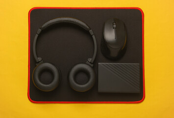 Wall Mural - Modern black gadgets on PC mouse pad. Yellow backgroud. Top view