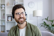 Happy middle-aged man wearing a headset and glasses, smiling during a video call in a comfortable, well-lit home setting.