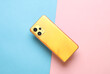Back side of yellow modern smartphone on pink blue background