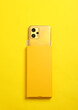 Modern yellow new smartphone with box on yellow background. Top view