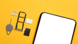 Smartphone with white blank screen, Tray with SIM and micro SD memory cards on a yellow background. Flat lay