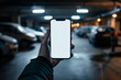 © Running opossum - Hand holding smartphone with blank screen using parking payment app in a dimly lit urban parking garage, convenience at your fingertips