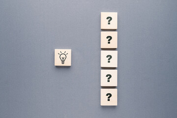 Wall Mural - A row of question marks on wooden blocks and a light bulb symbol, many questions lead to the success idea, things to find out, learning concept