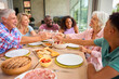 © Monkey Business - Three Generation Family Indoors At Home Doing Cheers With Water Before Eating Meal Together