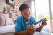 © Monkey Business - Teenage Boy Lying On Bed At Home Playing With Handheld Gaming Device
