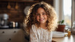 © Oleksandra - Portrait of a happy, cute kid, curly girl smiling at camera at kitchen at bright home.