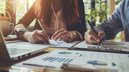 Leinwandbilder - Two professionals working together at a table with graphs and data, focusing intently on documents.