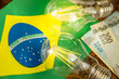 Cost of electricity in Brazil, economic and financial concept. Brazilian flag, two burning light bulbs and money