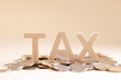 Word Tax made of wooden letters and coins on beige background