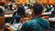 © Prostock-studio - A focused student is jotting down notes during a lecture in a crowded university hall.