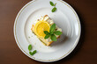 Lemon cake with lemon slice and peppermint leaf on top, white plate, top view