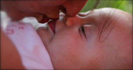 Wall Mural - Mother kissing newborn baby infant outdoors