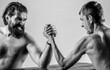 © Yevhen - Heavily muscled bearded man arm wrestling a puny weak man. Two man's hands clasped arm wrestling, strong and weak, unequal match. Black and white