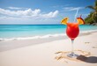 A tropical cocktail on a sandy beach with a turquoise ocean and blue sky in the background