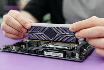 system administrator installing random access memory into motherboard, assembling PC of different accessories or components, close-up view of hands, computer repair and maintenance concept