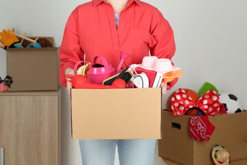 Wall Mural - Woman holding box of unwanted stuff indoors, closeup