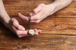 Man holding chain with elegant pocket watch at wooden table, closeup. Space for text