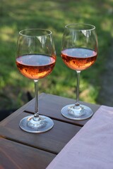 Wall Mural - Glasses of rose wine on wooden table in garden