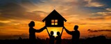 Fototapeta  - The silhouette of a family holding up a house shaped form with a window in front of a sunset