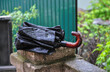 a forgotten wet umbrella on a stone railing. wet folded black umbrella on stone railing