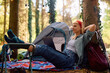 Relaxed woman using laptop while camping in forest.