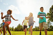 © peopleimages.com - Happy friends, diversity and running with children in nature for fun, playful day or summer at park. Group of excited kids or youth enjoying sunny outdoor holiday or weekend on grass field together