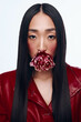 Beautiful woman with long black hair wearing a red jacket and holding a flower in her mouth