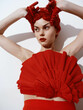 Elegant woman in red dress posing with fan in her hair with hands on head in stylish and graceful pose