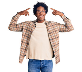 Wall Mural - handsome african american man with afro hair wearing casual clothes and glasses smiling pointing to 