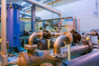 An array of metal pipes, valves, and pumps within an industrial plant.