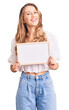 © Krakenimages.com - Young caucasian woman with blond hair holding blank empty banner looking positive and happy standing and smiling with a confident smile showing teeth