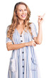 © Krakenimages.com - Young caucasian woman with blond hair wearing summer dress smiling happy pointing with hand and finger to the side