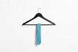 Hanger with light blue necktie on white wall