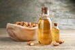 Almond oil in bottles and nuts on wooden table, closeup