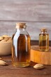 Almond oil in bottles and bowl with nuts on wooden table, closeup