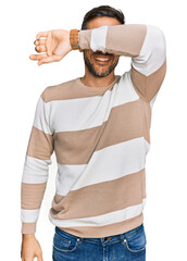 Poster - Handsome man with beard wearing casual clothes and glasses covering eyes with arm smiling cheerful and funny. blind concept.