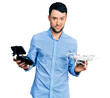 © Krakenimages.com - Hispanic man with beard using drone with remote control clueless and confused expression. doubt concept.