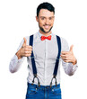 © Krakenimages.com - Hispanic man with beard wearing hipster look with bow tie and suspenders success sign doing positive gesture with hand, thumbs up smiling and happy. cheerful expression and winner gesture.