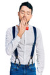 © Krakenimages.com - Hispanic man with beard wearing hipster look with bow tie and suspenders bored yawning tired covering mouth with hand. restless and sleepiness.