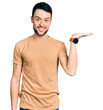 © Krakenimages.com - Hispanic man with beard wearing casual t shirt smiling cheerful presenting and pointing with palm of hand looking at the camera.