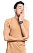 © Krakenimages.com - Hispanic man with beard wearing casual t shirt bored yawning tired covering mouth with hand. restless and sleepiness.