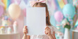 © SnowElf - Little kid girl in pastel clothing holding vertical empty white blank, invitation card mockup, copy space.